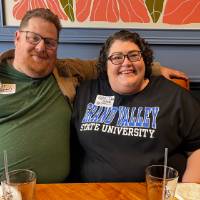 Two alumni smile at a booth